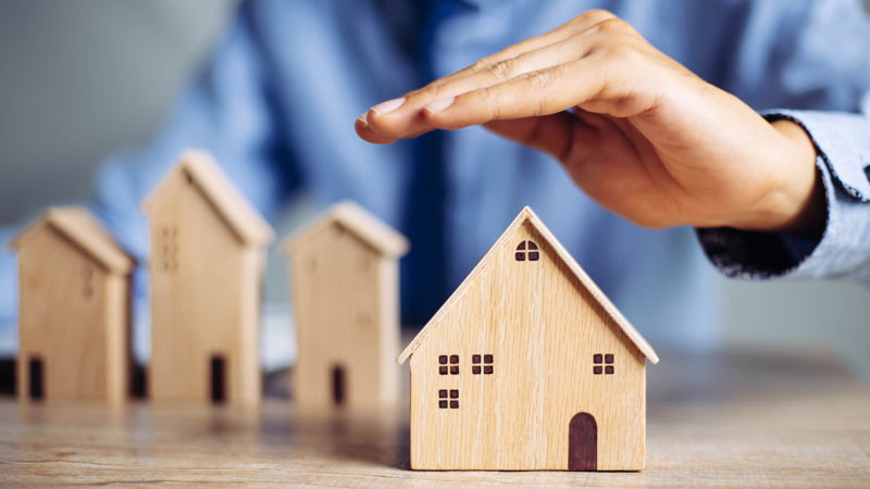 Mão protege uma casa de madeira